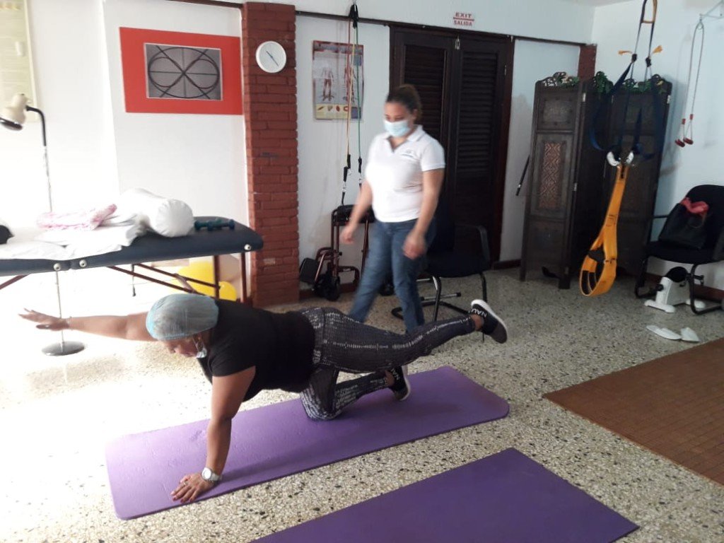 Paciente haciendo un ejercicio en colchoneta, acompañada por una terapeuta