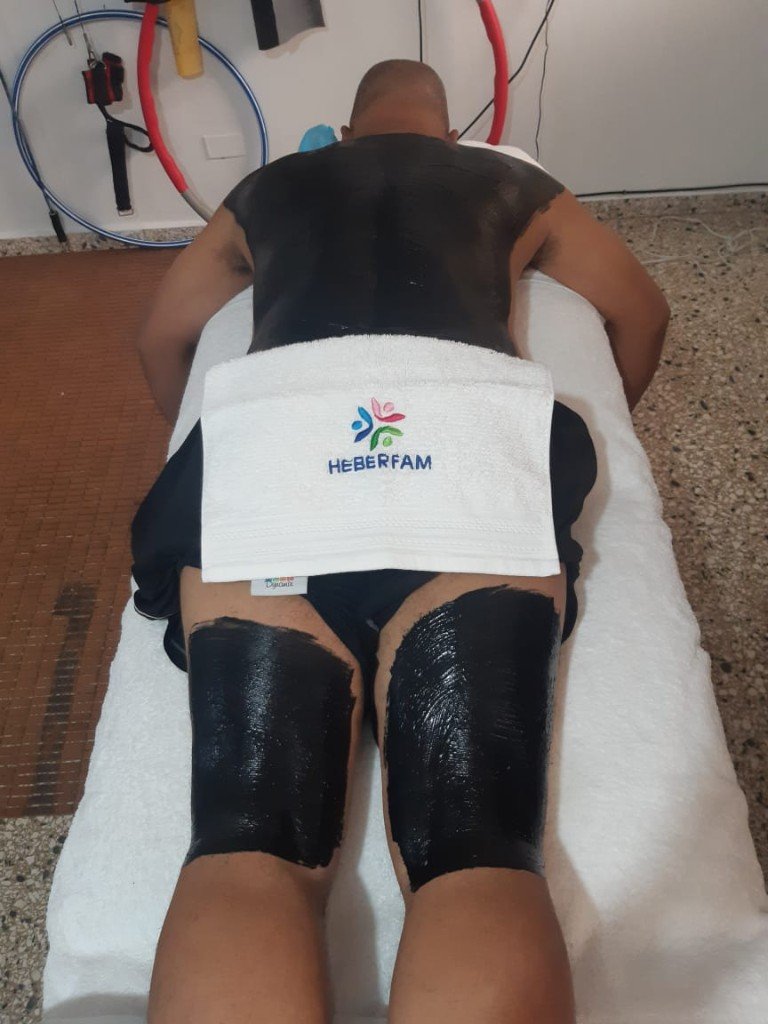 Paciente boca abajo con fango en la espalda y los muslos