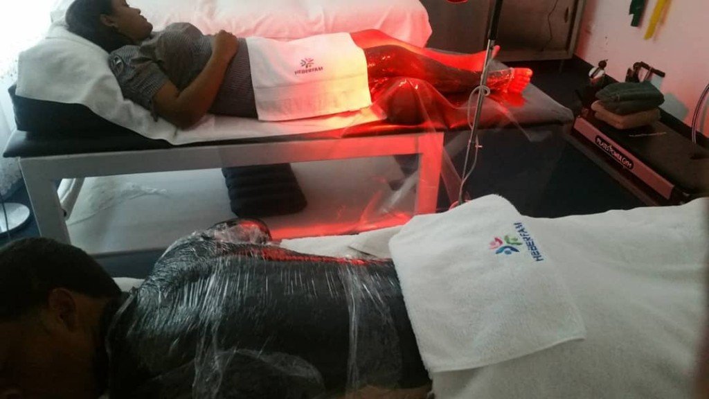 Lámpara de luz roja sobre las piernas durante una sesión en camilla